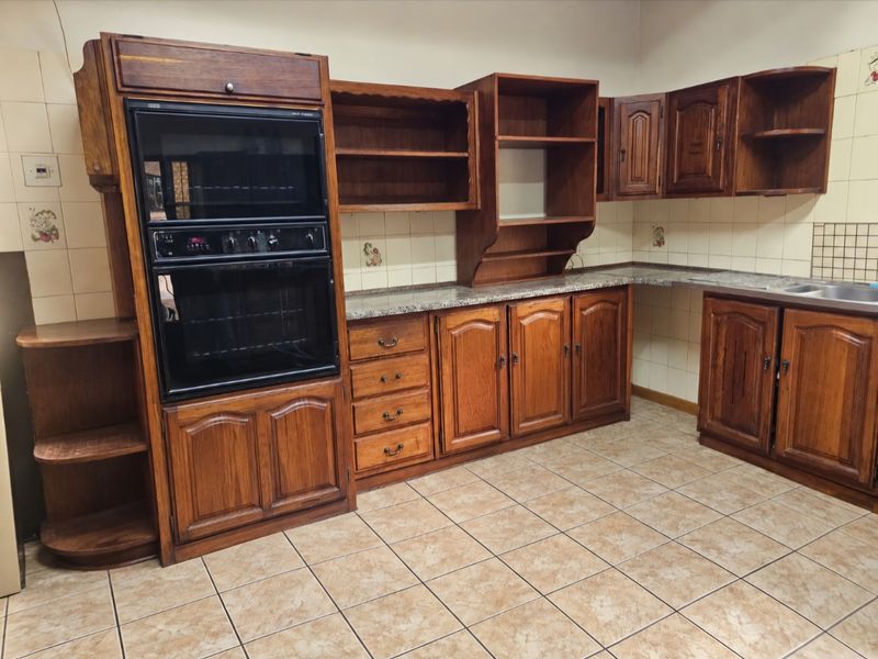 A functional kitchen featuring traditional wooden cabinetry, a built-in double oven, laminate countertops, and a double bowl stainless steel sink with tiled backsplash.