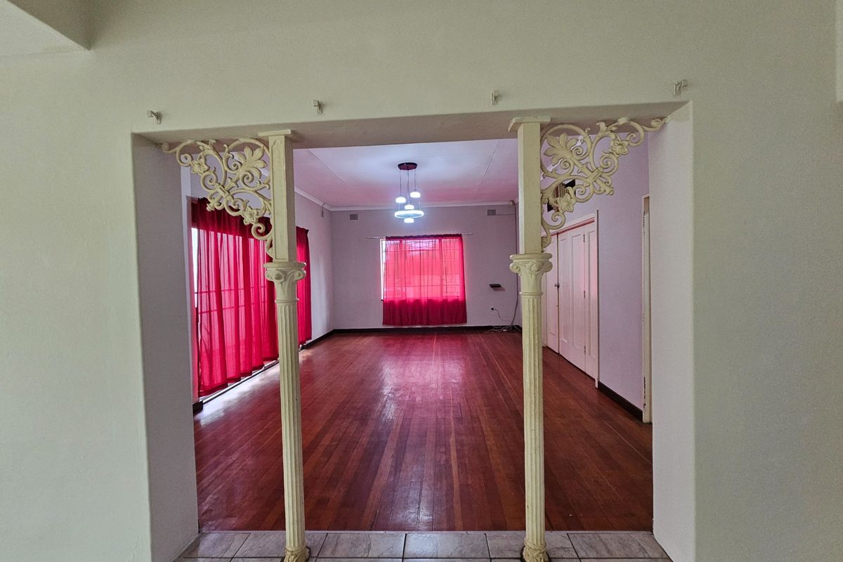 Spacious living area featuring original hardwood flooring and decorative cast iron columns, offering a blank canvas for interior design updates.