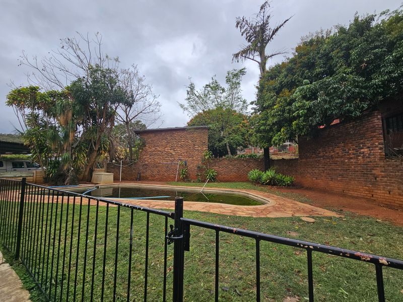 Outdoor pool area featuring a swimming pool, stone paving, and brick boundary walls, requiring maintenance and landscaping to restore its appeal.