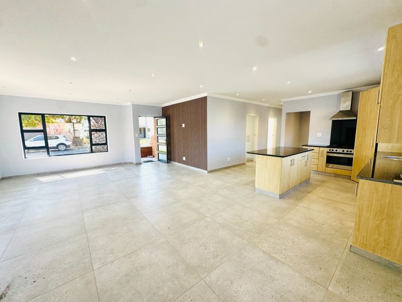 Spacious open-plan living area featuring large format floor tiles, a modern kitchen with island, and a stylish timber slat feature wall.