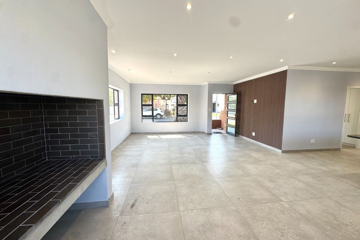 Spacious open-plan living area featuring large format floor tiles, a built-in fireplace, and a modern timber slat feature wall with recessed lighting.