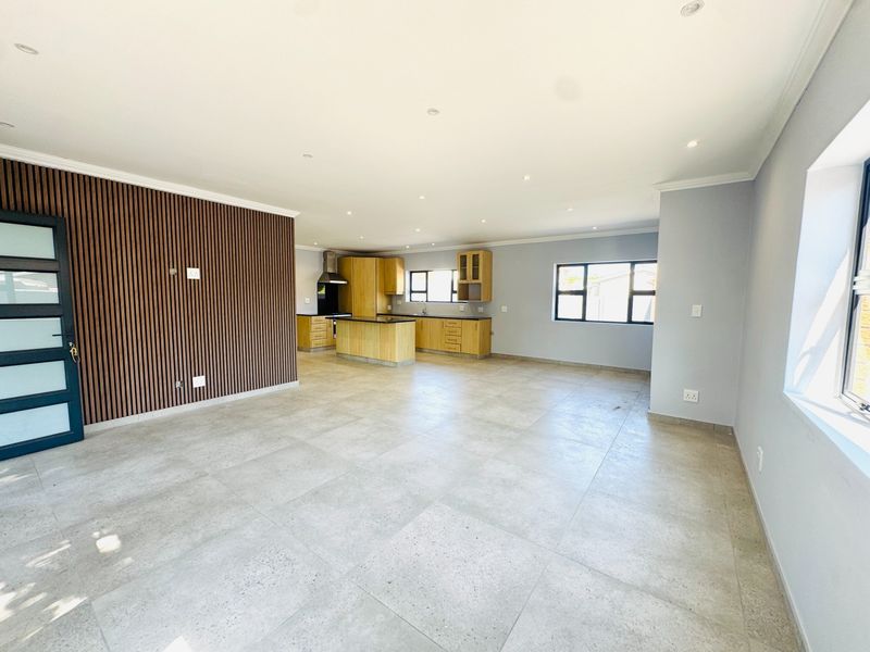 Spacious open-plan living and kitchen area featuring modern tiled floors, a timber slat feature wall, and contemporary kitchen cabinetry with an island.