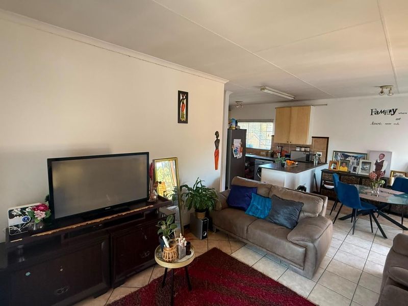 Open plan living and dining area featuring tiled flooring and an adjoining kitchen with built-in cabinetry and countertops.