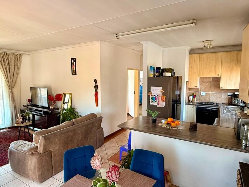Open-plan living and kitchen area featuring tiled flooring, a breakfast bar, and functional built-in cabinetry with integrated cooking appliances.