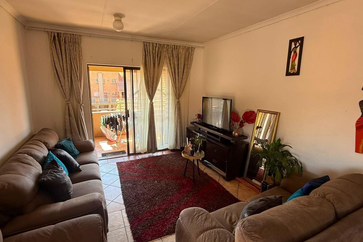 A comfortable living room featuring tiled flooring and a sliding glass door that opens onto a private balcony.