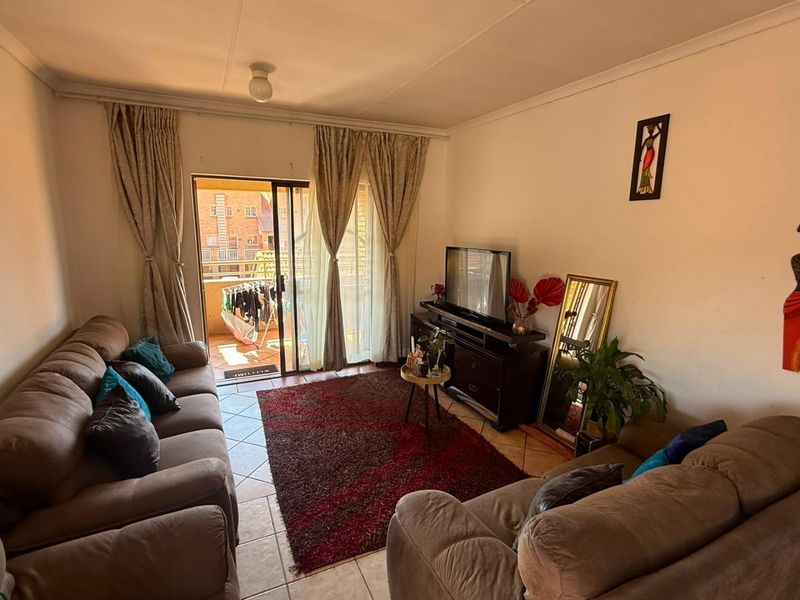 A comfortable living room featuring tiled flooring and a sliding glass door that opens onto a private balcony.