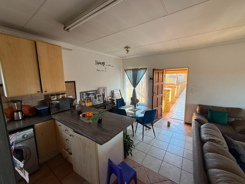 Open-plan living and kitchen area featuring tiled flooring, laminate cabinetry, and direct access to an outdoor patio space.