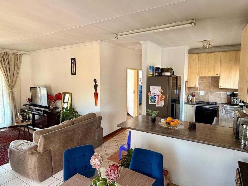 Open-plan living area featuring a functional kitchen with built-in cabinetry, breakfast bar, and tiled flooring throughout the combined space.