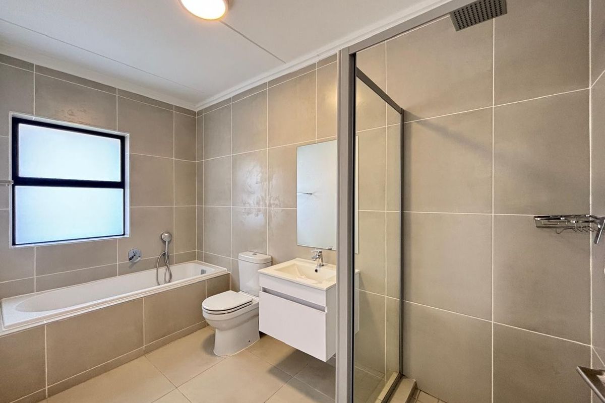 Modern bathroom featuring a built-in bathtub, a separate glass-enclosed shower with a rain shower head, and a sleek wall-mounted vanity.
