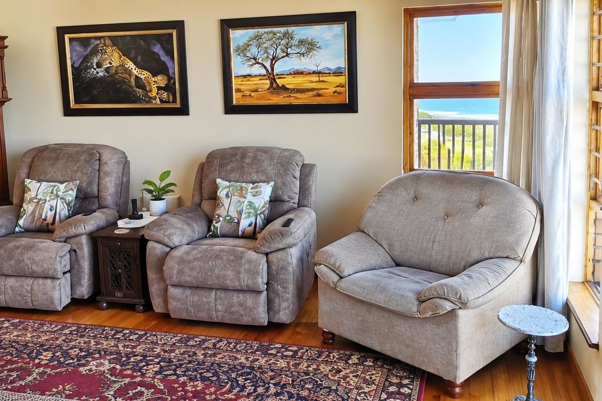 A comfortable living area featuring hardwood flooring and large windows with direct access to an outdoor deck and ocean views.