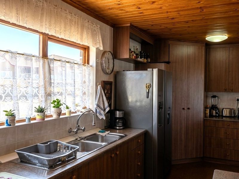 A functional kitchen featuring timber tongue and groove ceilings, laminate countertops, and ample built-in cabinetry with a double bowl sink.