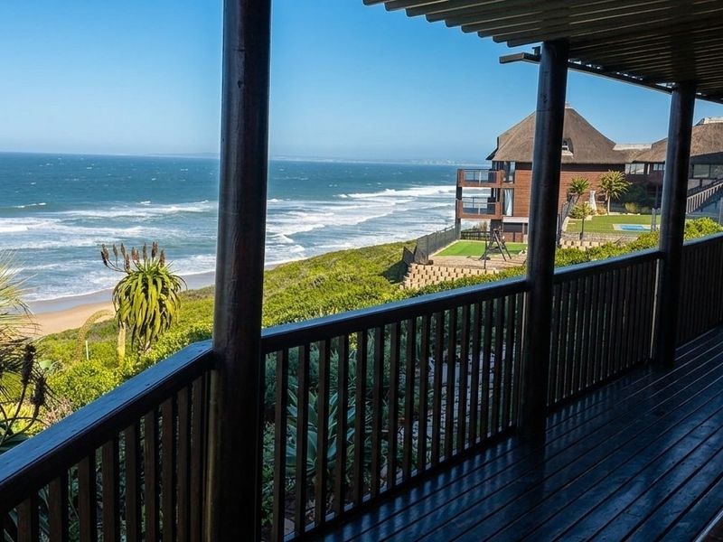A spacious covered timber balcony offering expansive ocean views, featuring sturdy timber support columns and a slatted ceiling, perfect for outdoor relaxation.