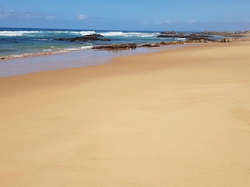 A scenic view of the sandy coastline and ocean waves, highlighting the natural landscape adjacent to the property.