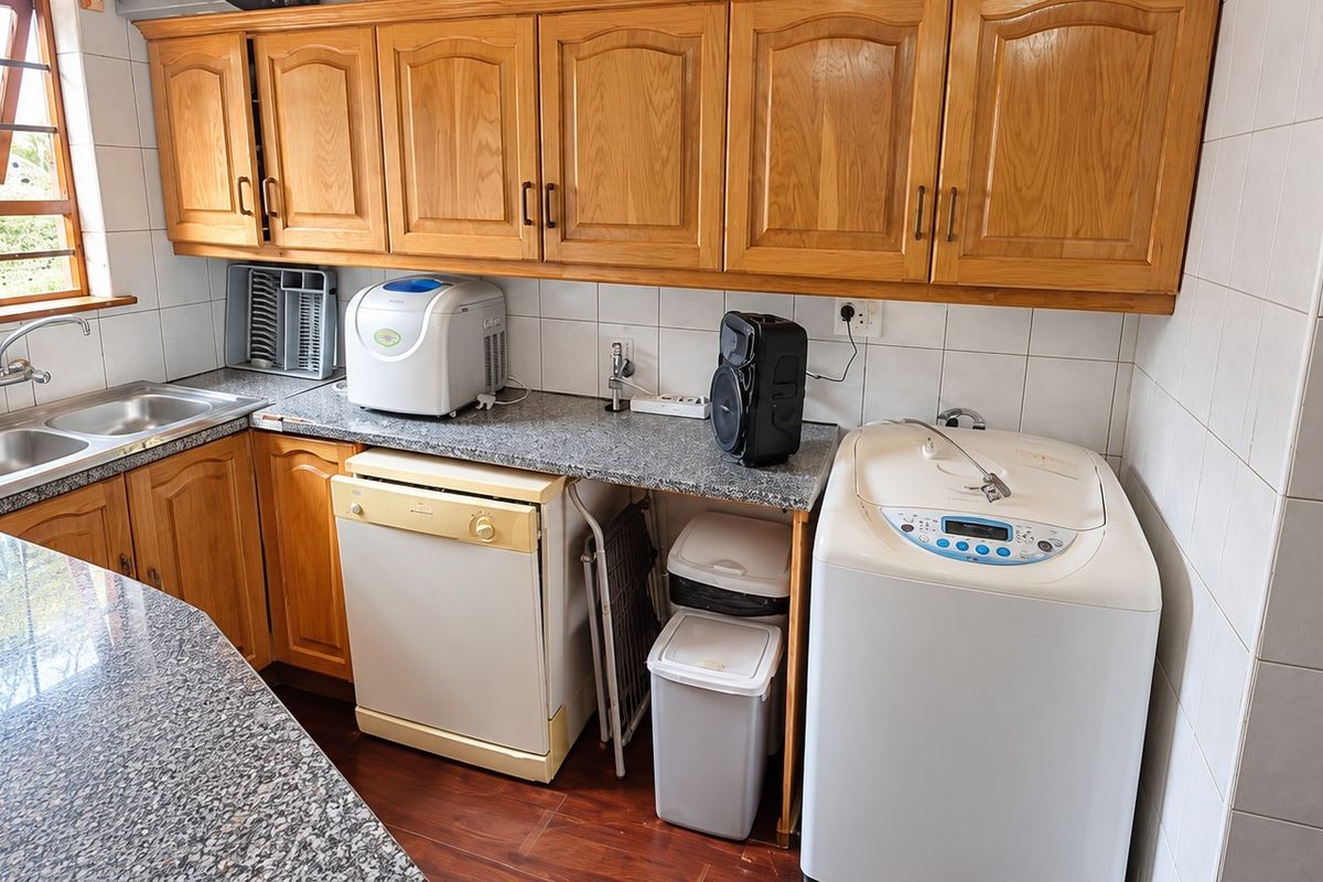A functional kitchen featuring wooden cabinetry, granite countertops, and a double basin sink, offering a practical layout with tiled backsplash and laminate flooring.