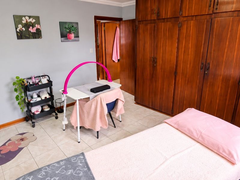 A bedroom featuring tiled flooring and extensive built-in wooden cabinetry, currently utilized as a treatment room.