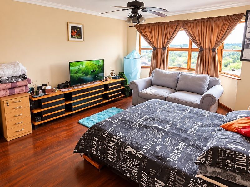 Spacious bedroom featuring hardwood flooring, a built-in wardrobe, and a ceiling fan, with large windows offering natural light and elevated views.