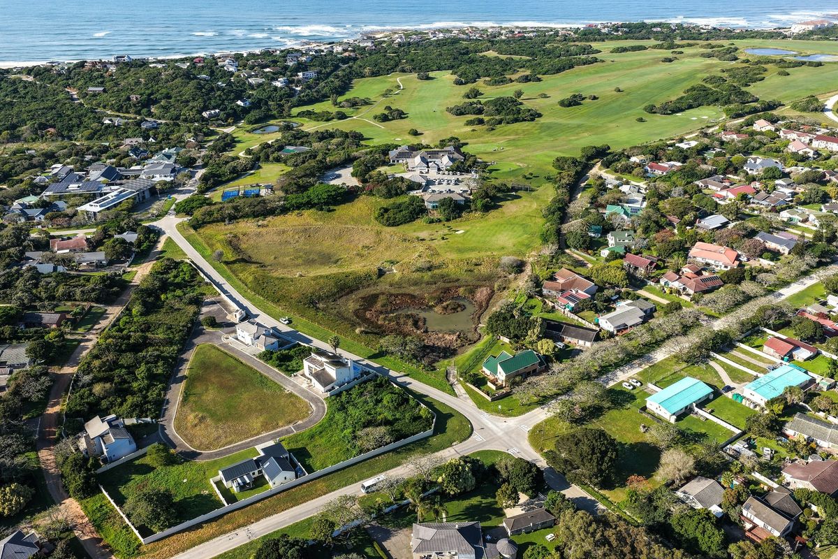 Aerial view of a vacant residential plot situated in a coastal estate, featuring proximity to a golf course and established neighborhood infrastructure.