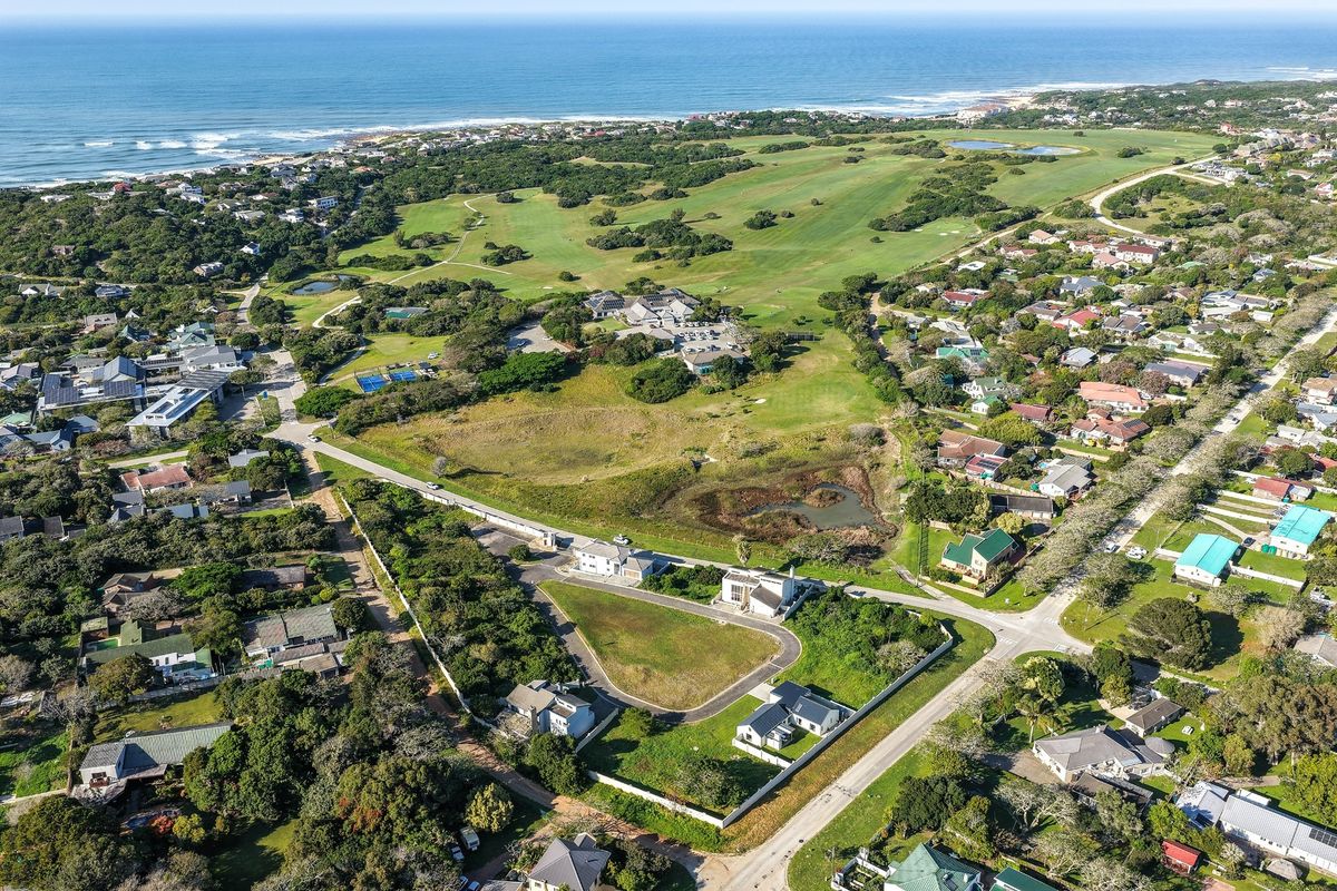 Aerial view of a vacant residential plot situated within a coastal estate, featuring established boundary walls and convenient access to local amenities.