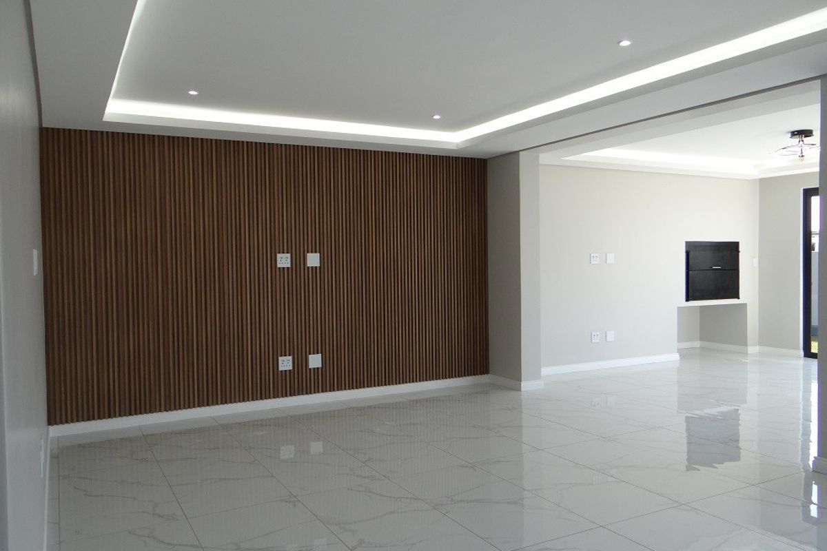 Spacious open-plan living area featuring modern porcelain floor tiles, a striking slatted timber feature wall, and elegant recessed cove lighting.