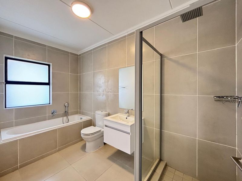 Modern bathroom featuring a built-in bathtub, a separate glass-enclosed shower with a rain shower head, and a sleek wall-mounted vanity.