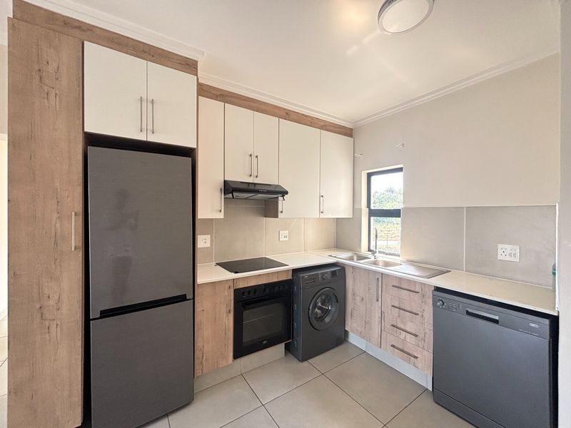 Modern kitchen featuring wood-look and cream cabinetry, integrated electric hob and oven, tiled splashbacks, and ample counter space with a double sink.