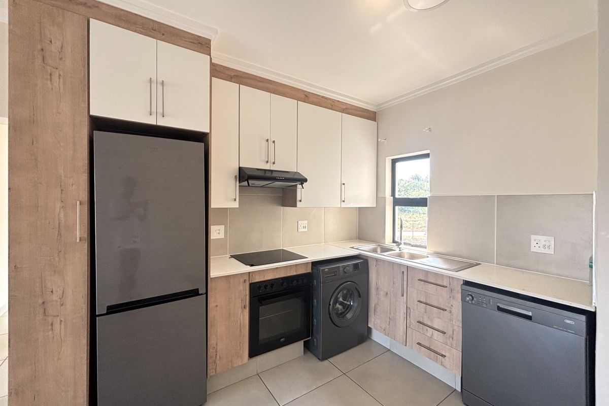 Modern kitchen featuring wood-look and cream cabinetry, integrated electric hob and oven, tiled splashbacks, and ample counter space with a double sink.