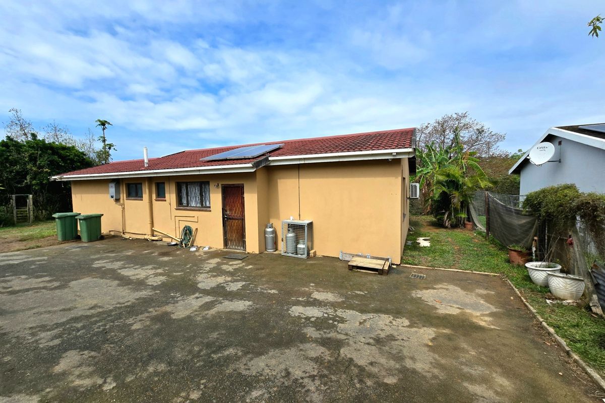 Rear exterior view of the house featuring a tiled roof with solar panels, concrete driveway, and secure access points.