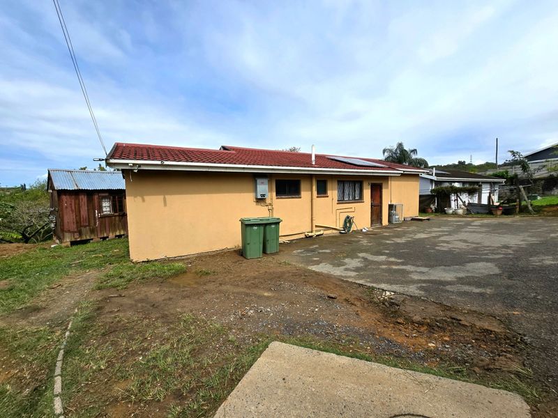 Rear view of the property featuring a tiled roof with solar water heater, asphalt driveway, and security gate access.