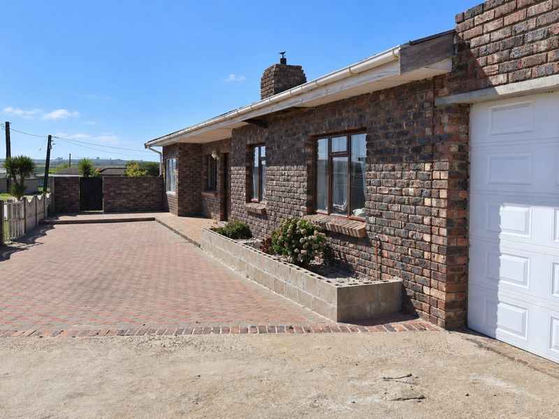 Front exterior view of a face brick house featuring a paved driveway, integrated garage, and a built-in brick planter box.