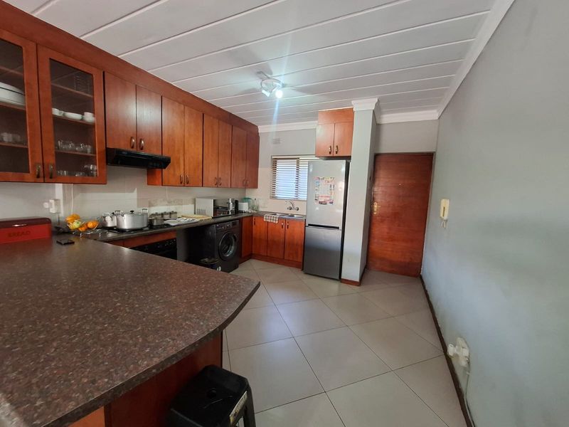 A functional kitchen featuring wooden cabinetry, laminate countertops, built-in oven, extractor fan, and tiled flooring, providing a practical workspace for daily cooking.