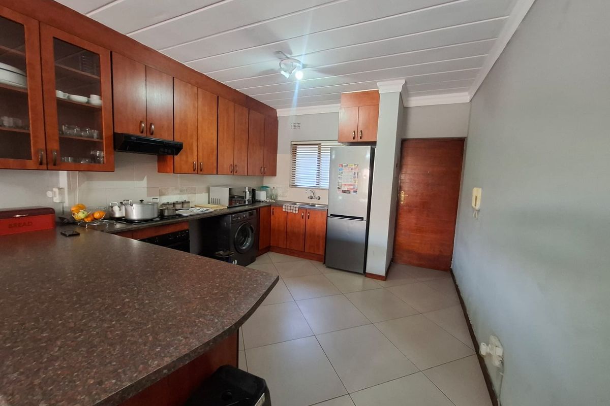 A functional kitchen featuring wooden cabinetry, laminate countertops, built-in oven, extractor fan, and tiled flooring, providing a practical workspace for daily cooking.