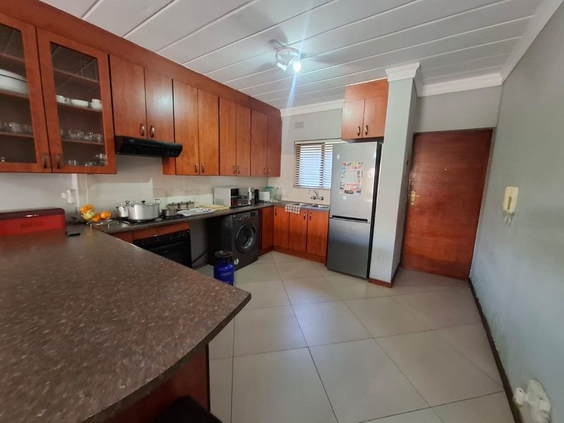 A functional kitchen featuring wooden cabinetry, laminate countertops, tiled flooring, and integrated appliances, offering a practical layout for daily use.