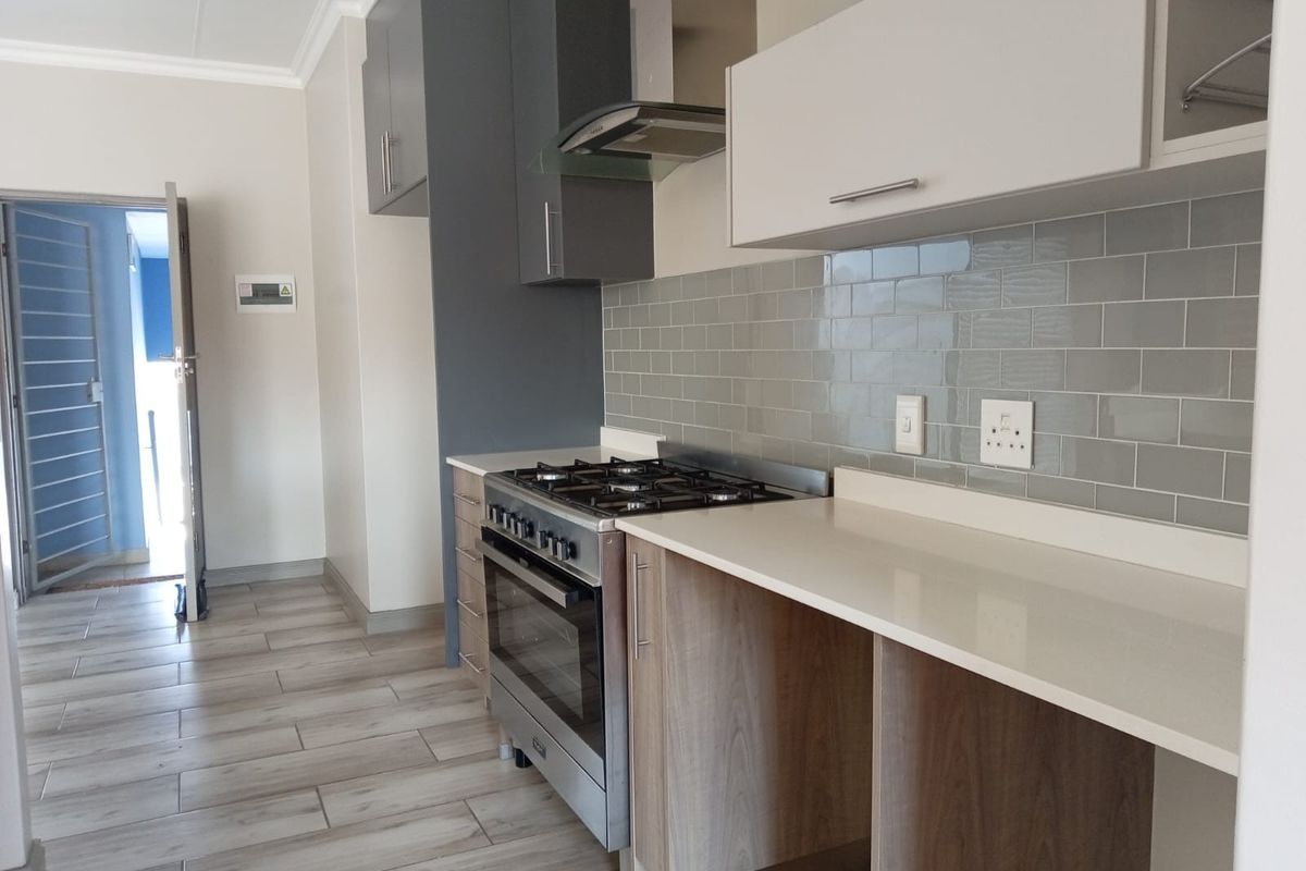 Modern kitchen featuring a gas stove, extractor fan, subway tile backsplash, quartz countertops, and ample built-in cabinetry with wood-look tiled flooring.