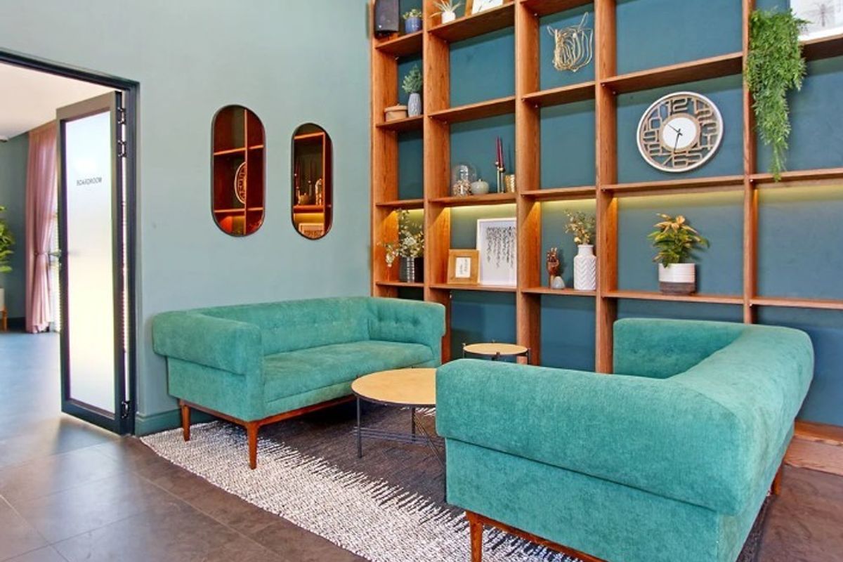 A modern living area featuring a large built-in wooden shelving unit with integrated LED lighting and sleek tiled flooring.