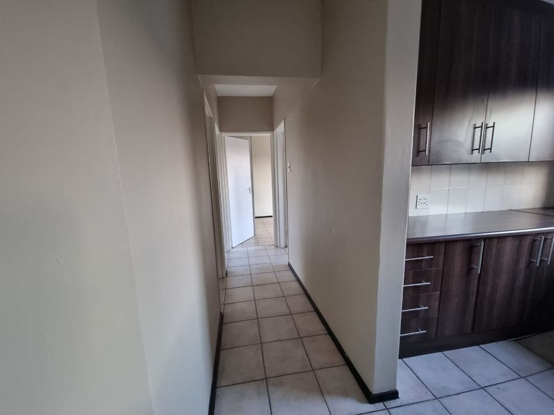 A view from the kitchen area looking into a tiled hallway leading to an adjacent room.