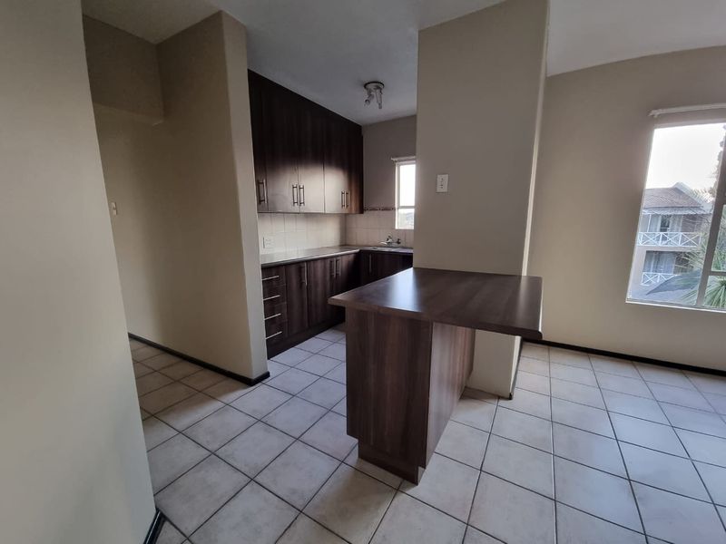 A functional kitchen featuring dark wood cabinetry, laminate countertops, a breakfast bar, and tiled flooring, offering a clean and practical layout.