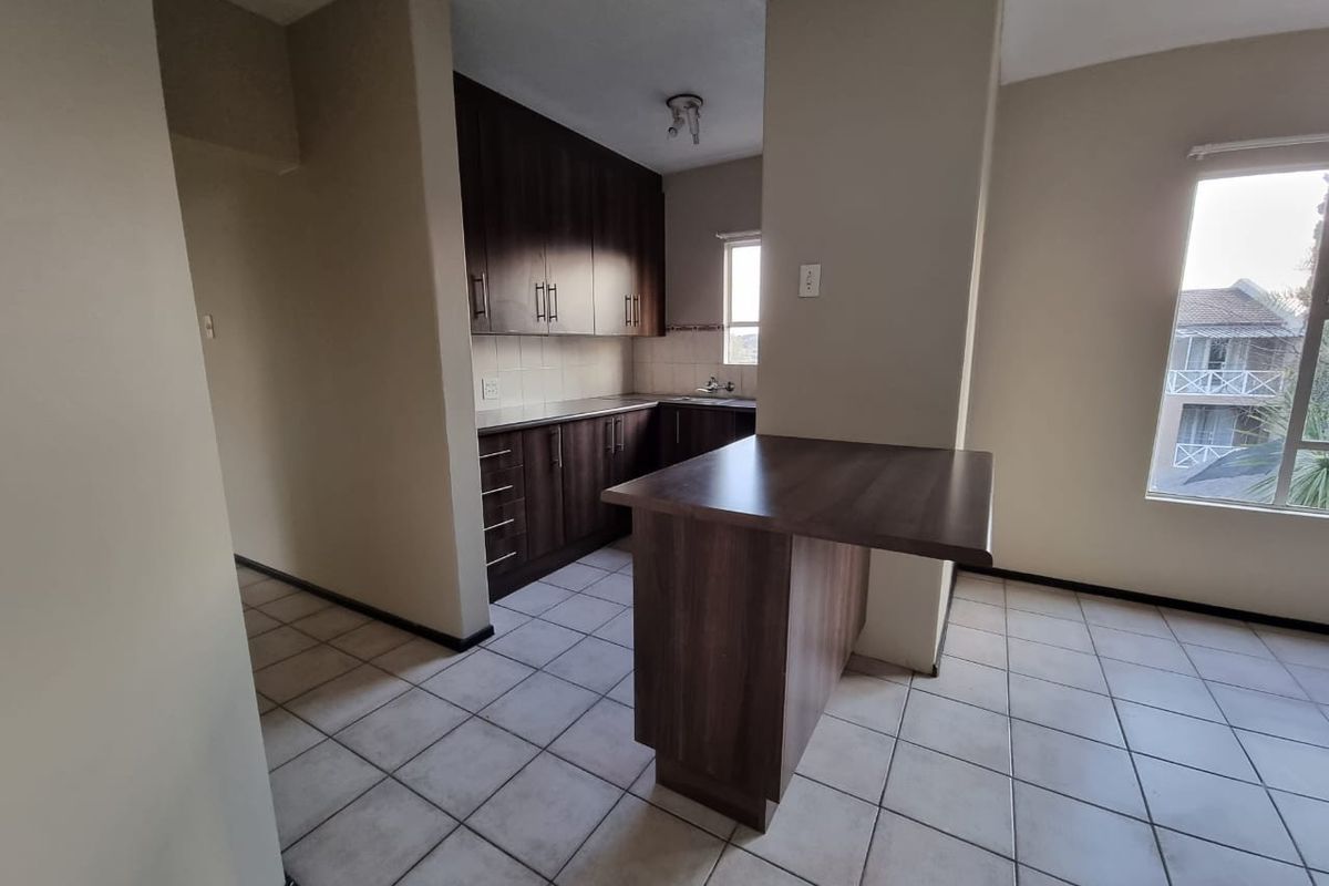 A functional kitchen featuring dark wood cabinetry, laminate countertops, a breakfast bar, and tiled flooring, offering a clean and practical layout.