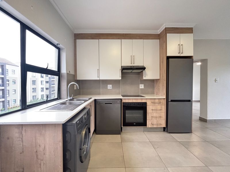Modern kitchen featuring light wood and white cabinetry, stone countertops, integrated appliances, and large windows providing ample natural light.