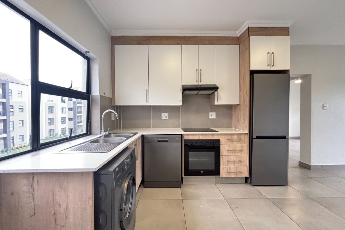 Modern kitchen featuring light wood and white cabinetry, stone countertops, integrated appliances, and large windows providing ample natural light.
