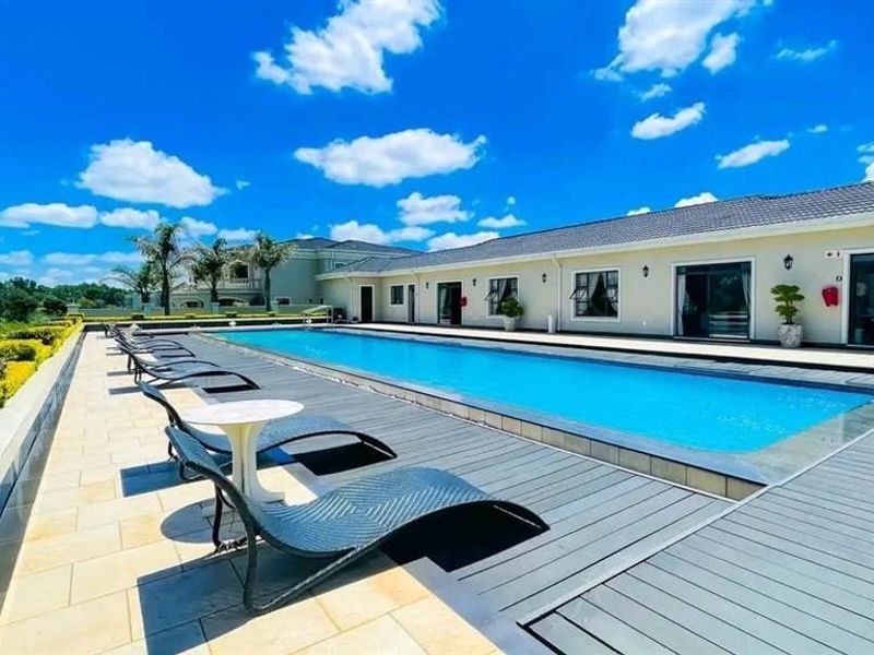 A well-maintained outdoor swimming pool area featuring composite decking, tiled patio surrounds, and direct access to the main residence via sliding glass doors.