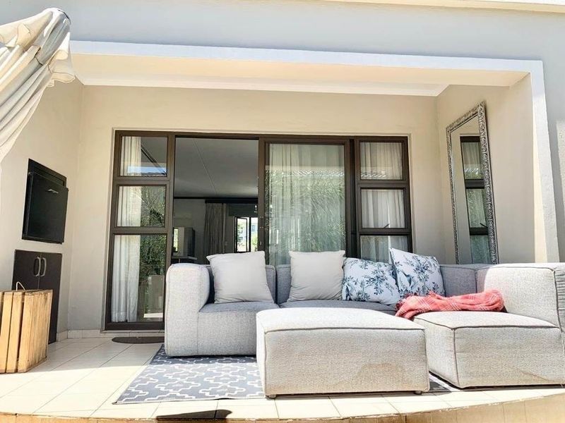 A covered patio area featuring tiled flooring, a built-in braai, and large sliding glass doors providing access to the interior living space.