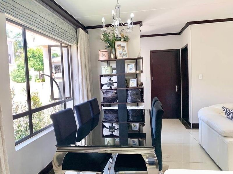 A bright and well-maintained dining area featuring large windows, tiled flooring, and a central chandelier, creating an inviting space for meals.
