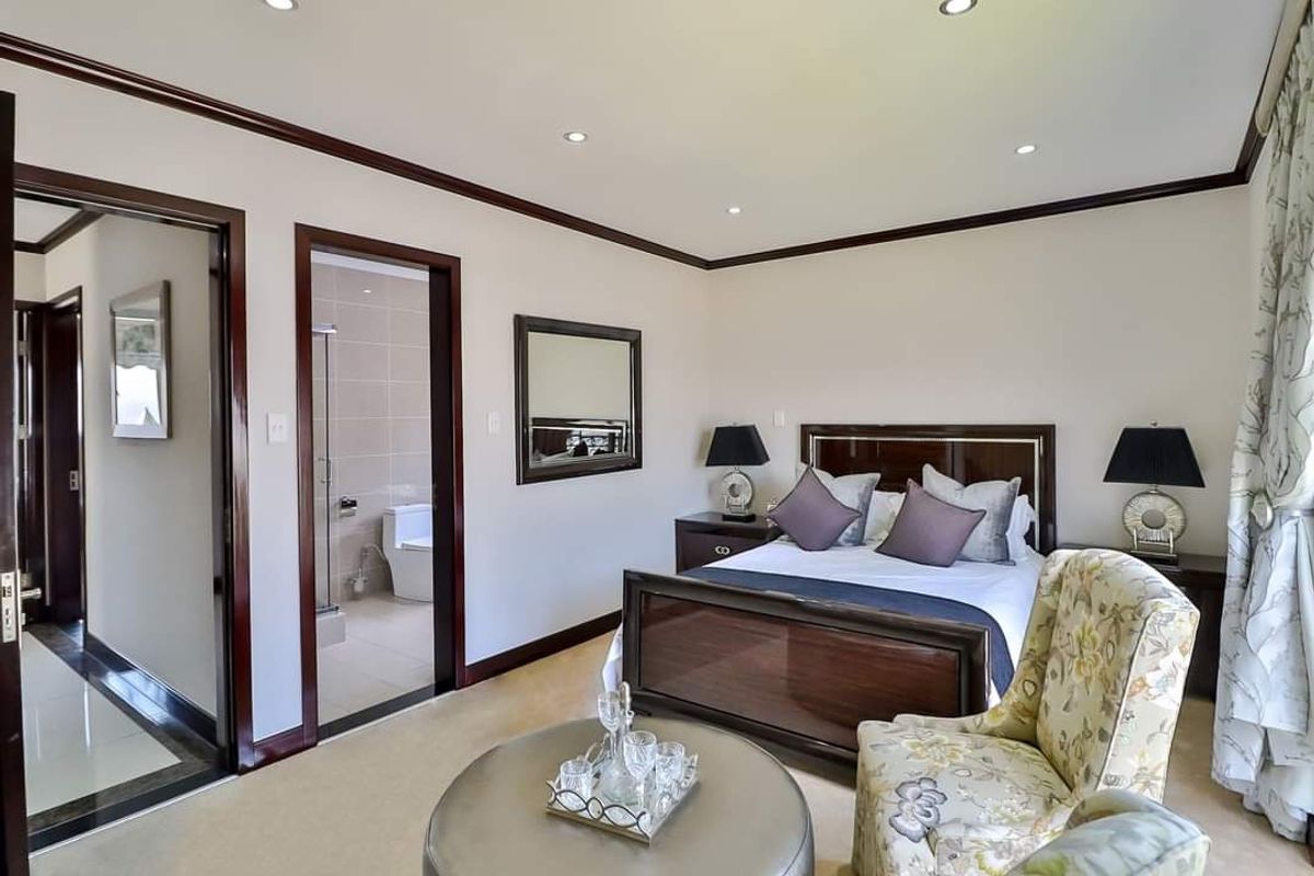 A well-maintained bedroom featuring recessed lighting, crown molding, and an adjoining en-suite bathroom with tiled flooring.