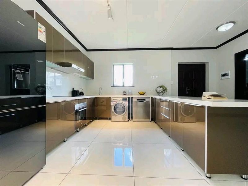 Modern kitchen featuring high-gloss cabinetry, integrated appliances, sleek countertops, and polished tiled flooring in a clean, contemporary layout.