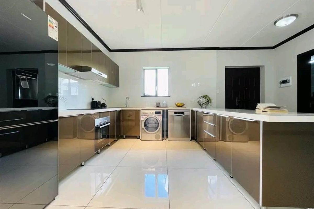 Modern kitchen featuring high-gloss cabinetry, integrated appliances, sleek countertops, and polished tiled flooring in a clean, contemporary layout.