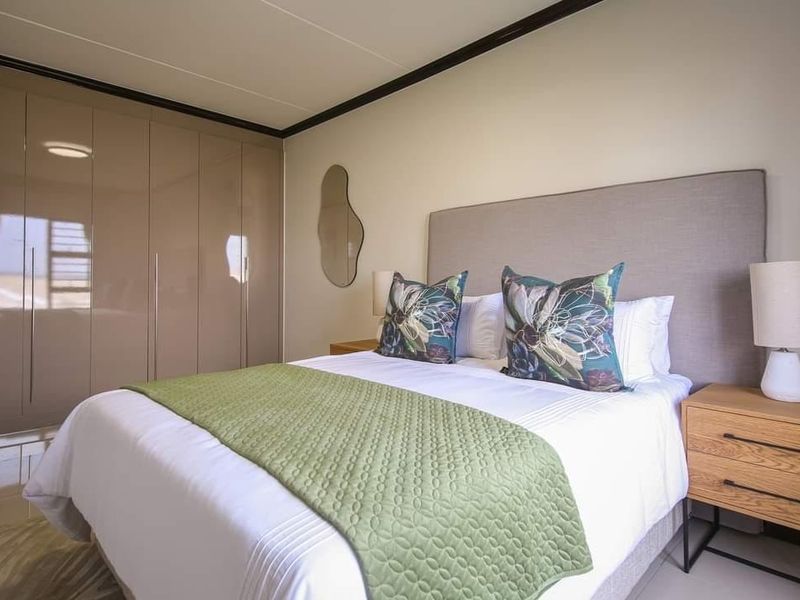 A well-maintained bedroom featuring neutral tones, sleek built-in cupboards, and polished tiled flooring, creating a clean and modern living space.