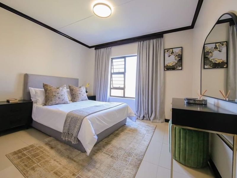 A well-maintained bedroom featuring tiled flooring, neutral walls, and a window with curtains, providing a clean and comfortable living space.