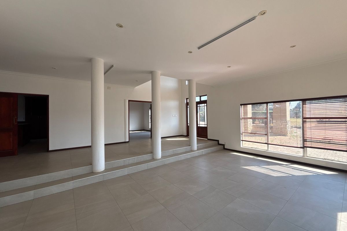 Spacious, open-plan living area featuring large windows, tiled flooring, and architectural columns, offering a bright and versatile space for interior design.
