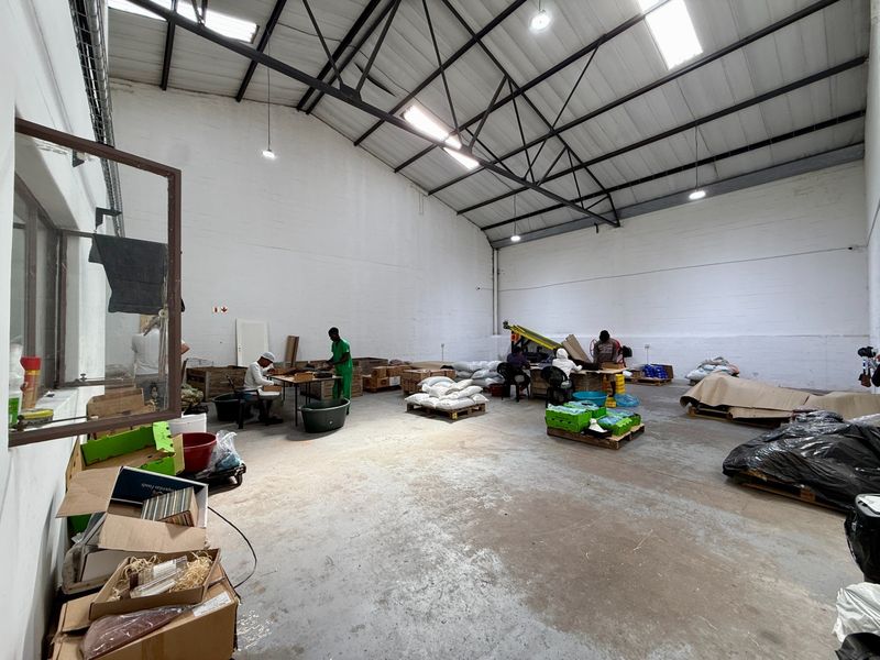 Spacious industrial warehouse unit featuring high ceilings with exposed steel trusses, skylights for natural light, and durable concrete flooring.