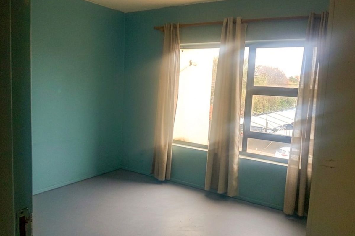 An empty bedroom featuring painted walls and an aluminium window frame, offering a blank canvas for potential interior design updates.